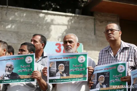 Palestinian members of Hamas legislative council and members of the factions hold banners during a protest to show solidarity with Leader of the northern Islamic Movement Sheikh Raed Salah who is in solitary confinement...