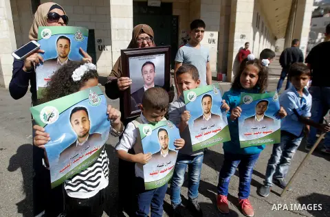 Palestinians hold banners during a protest demanding Israel return the bodies of Palestinians who allegedly stabbed Israelis, in the West Bank city of Hebron, on Oct. 28, 2016. Photo by Wisam Hashlamoun