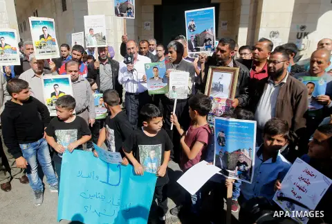 Palestinians hold banners during a protest demanding Israel return the bodies of Palestinians who allegedly stabbed Israelis, in the West Bank city of Hebron, on Oct. 28, 2016. Photo by Wisam Hashlamoun