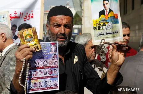 Palestinians hold banners during a protest demanding Israel return the bodies of Palestinians who allegedly stabbed Israelis, in the West Bank city of Hebron, on Oct. 28, 2016. Photo by Wisam Hashlamoun