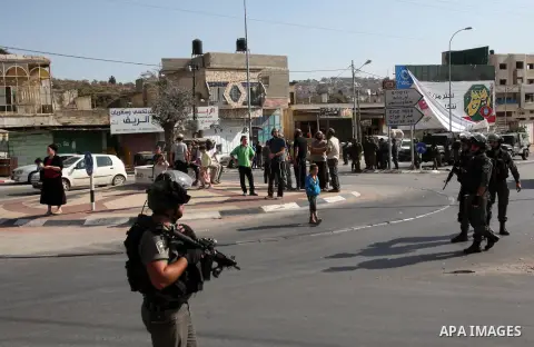 Israeli security forces stand guard as settlers demonstrate against Palestinian stones throwers on October 28, 2016 on the main road of the village of Hawara in the northern West Bank. Photo by Nedal Eshtayah