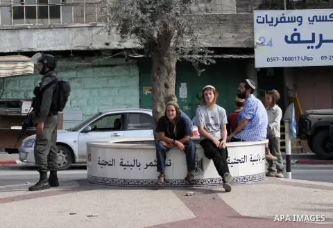 Israeli security forces stand guard as settlers demonstrate against Palestinian stones throwers on October 28, 2016 on the main road of the village of Hawara in the northern West Bank. Photo by Nedal Eshtayah