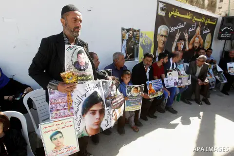 Palestinians hold banners during a protest to show solidarity with Palestinian prisoners in Israeli jails, in front of Red cross office in the West Bank city of Hebron, on October 31, 2016. Photo by Wisam Hashlamoun