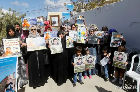 Palestinians hold banners during a protest to show solidarity with Palestinian prisoners in Israeli jails, in front of Red cross office in the West Bank city of Hebron, on October 31, 2016. Photo by Wisam Hashlamoun