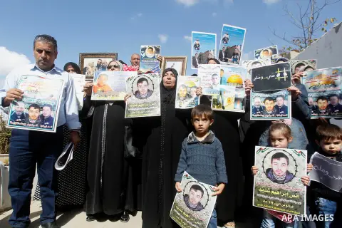 Palestinians hold banners during a protest to show solidarity with Palestinian prisoners in Israeli jails, in front of Red cross office in the West Bank city of Hebron, on October 31, 2016. Photo by Wisam Hashlamoun
