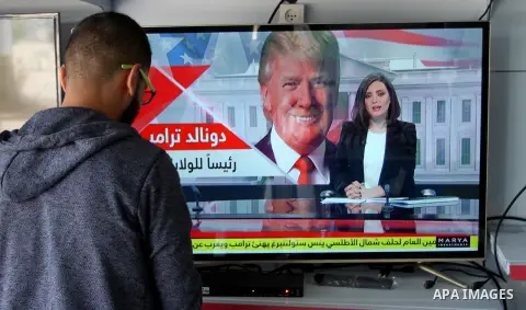A Palestinian man watches broadcasting of the 2016 U.S. presidential election results on TV in Rahaf in the southern Gaza strip, on November 9, 2016. Republican Donald Trump has been elected the 45th president of the Uni...