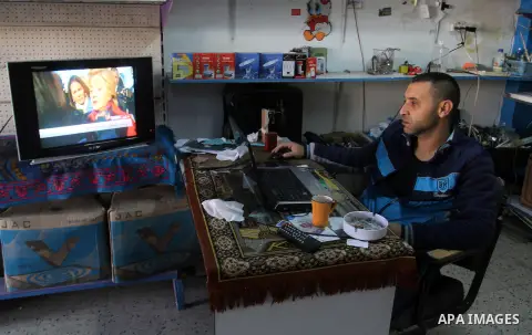 A Palestinian man watches broadcasting of the 2016 U.S. presidential election results on TV in Rahaf in the southern Gaza strip, on November 9, 2016. Republican Donald Trump has been elected the 45th president of the Uni...