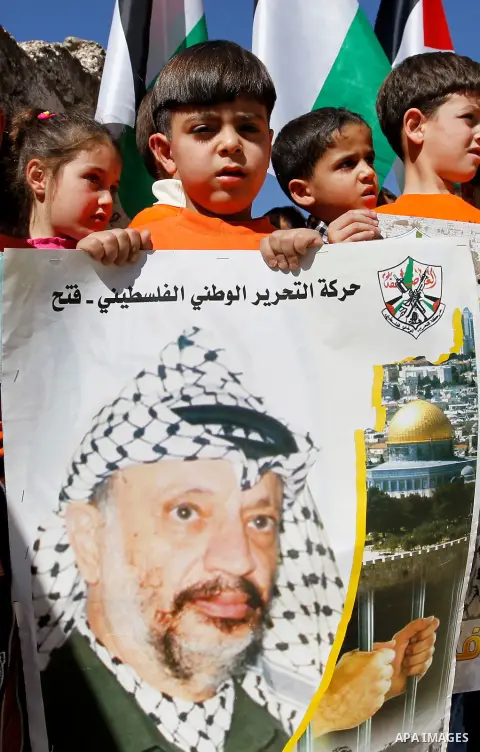 Palestinian children hold posters of the late Palestinian leader Yasser Arafat to mark the 12 anniversary of his death in the West Bank city of Hebron, 10 November 2016. Photo by Wisam Hashlamoun