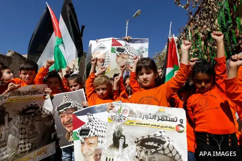 Palestinian children hold posters of the late Palestinian leader Yasser Arafat to mark the 12 anniversary of his death in the West Bank city of Hebron, 10 November 2016. Photo by Wisam Hashlamoun