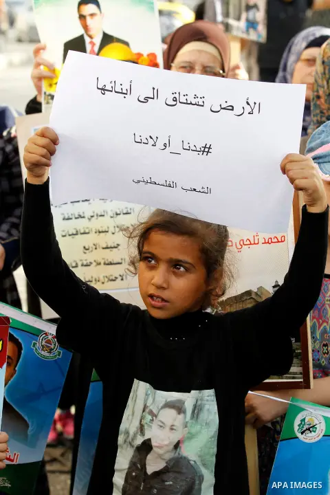 Palestinians hold banners during a protest demanding Israel return the bodies of Palestinians who allegedly stabbed Israelis, in the West Bank city of Hebron, on Nov. 13, 2016. Photo by Wisam Hashlamoun