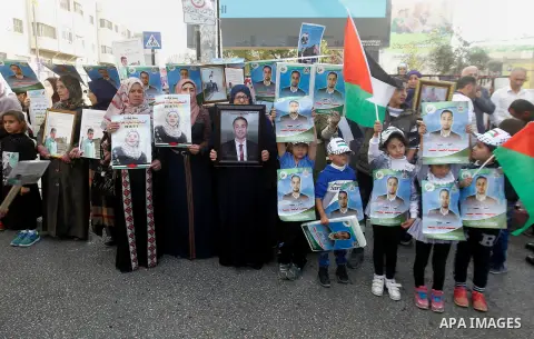 Palestinians hold banners during a protest demanding Israel return the bodies of Palestinians who allegedly stabbed Israelis, in the West Bank city of Hebron, on Nov. 13, 2016. Photo by Wisam Hashlamoun