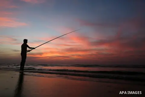 A Palestinian man uses a hook to fishing off the beach of Gaza City on November 14, 2016. Photo by Yasser Qudih