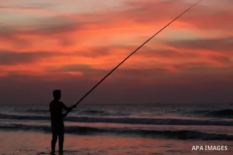 A Palestinian man uses a hook to fishing off the beach of Gaza City on November 14, 2016. Photo by Yasser Qudih