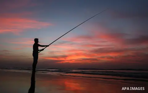 A Palestinian man uses a hook to fishing off the beach of Gaza City on November 14, 2016. Photo by Yasser Qudih