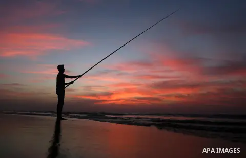 A Palestinian man uses a hook to fishing off the beach of Gaza City on November 14, 2016. Photo by Yasser Qudih