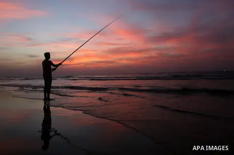 A Palestinian man uses a hook to fishing off the beach of Gaza City on November 14, 2016. Photo by Yasser Qudih