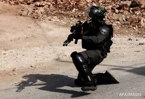 An Israeli border policeman aims his weapon at Palestinian protesters during clashes following a demonstration against the expropriation of Palestinian land by Israel on November 18, 2016 in the village of Kfar Qaddum, n...