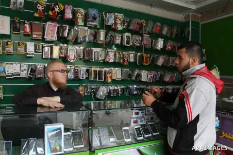 A Palestinian man work at his mobile phone shop in Rafah in the southern Gaza strip, on November 20, 2016. Interior Ministry in Gaza are trying to stop the sale and distribution of pre-paid SIM cards from Israeli cellula...