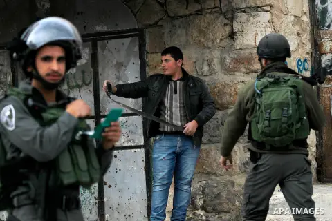 An Israeli soldier checks a Palestinian man at a checkpoint in the West Bank city of Hebron, on Nov. 22, 2016. Photo by Wisam Hashlamoun