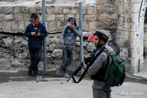 An Israeli soldier checks a Palestinian man at a checkpoint in the West Bank city of Hebron, on Nov. 22, 2016. Photo by Wisam Hashlamoun