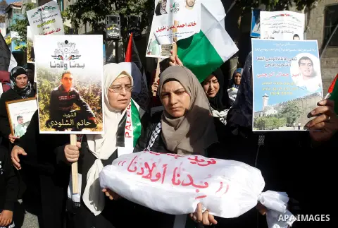 Palestinians hold banners during a protest demanding Israel return the bodies of Palestinians who allegedly stabbed Israelis, in the West Bank city of Hebron, on November 28, 2016. Photo by Wisam Hashlamoun