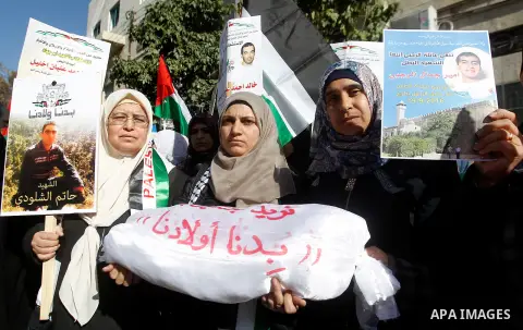 Palestinians hold banners during a protest demanding Israel return the bodies of Palestinians who allegedly stabbed Israelis, in the West Bank city of Hebron, on November 28, 2016. Photo by Wisam Hashlamoun