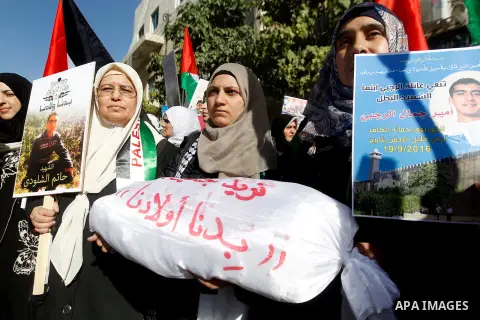 Palestinians hold banners during a protest demanding Israel return the bodies of Palestinians who allegedly stabbed Israelis, in the West Bank city of Hebron, on November 28, 2016. Photo by Wisam Hashlamoun