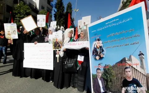 Palestinians hold banners during a protest demanding Israel return the bodies of Palestinians who allegedly stabbed Israelis, in the West Bank city of Hebron, on November 28, 2016. Photo by Wisam Hashlamoun
