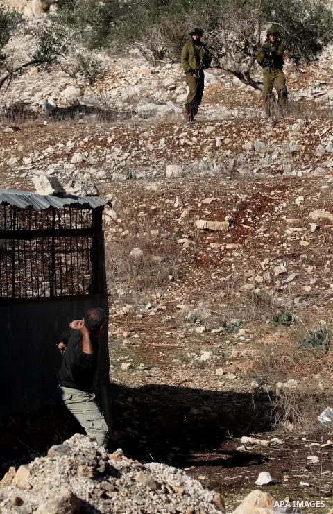 A Palestinian protester uses a slingshot to hurl stones towards Israeli security forces during clashes following a demonstration against the expropriation of Palestinian land by Israel in the village of Kfar Qaddum, near...
