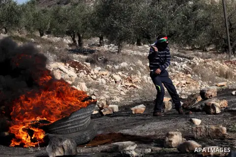 A Palestinian protester uses a slingshot to hurl stones towards Israeli security forces during clashes following a demonstration against the expropriation of Palestinian land by Israel in the village of Kfar Qaddum, near...