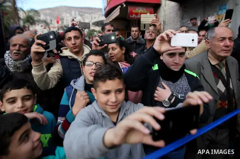 Palestinians take a photo with mobile as Muslim Sufis play musical instruments during a ceremony commemorating the birth of Prophet Mohammed, known in Arabic as "Mawlid al-Nabawi", in the West Bank city of Nablus on Dece...