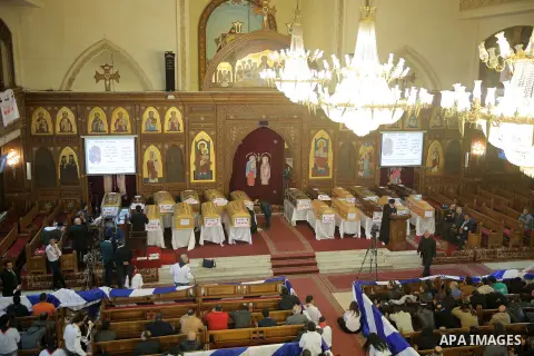 Egyptian clergymen stand next to the coffins of the victims of a bomb explosion that targeted a Coptic Orthodox Church the previous day in Cairo, during their funeral in the Egyptian capital's Nassr City neighbourhood on...
