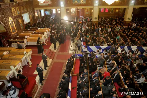 Egyptians stand next to the coffins of the victims of a bomb explosion that targeted a Coptic Orthodox Church the previous day in Cairo, during their funeral in the Egyptian capital's Nassr City neighbourhood on December...