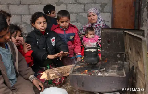 Palestinians warm themselves around a fire during the winter storm in Khan Younis, in the southern Gaza Strip on December 14, 2016. Photo by Ashraf Amra