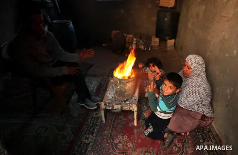 Palestinians warm themselves around a fire during the winter storm in Khan Younis, in the southern Gaza Strip on December 14, 2016. Photo by Ashraf Amra