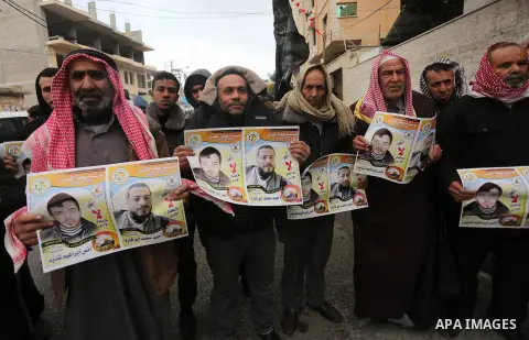 Palestinian hold banners during a protest to show solidarity with prisoner on hunger strike, in front of Red Cross, in Gaza city, on December 14, 2016. Photo by Mohammed Asad