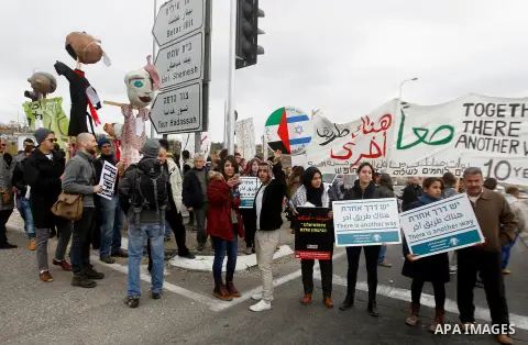 Peace activists hold placards during a joint Israeli-Palestinian peace march along the Israeli controversial separation wall in the West Bank city of Beit Jala between Bethlehem and Jerusalem, on December 16, 2016. Photo...