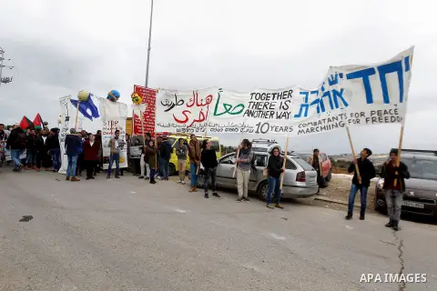 Peace activists hold placards during a joint Israeli-Palestinian peace march along the Israeli controversial separation wall in the West Bank city of Beit Jala between Bethlehem and Jerusalem, on December 16, 2016. Photo...