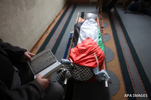 A man reads the Koran near the body of Palestinian Rahiq Birawi, who according to the Israeli police was shot dead after she had advanced towards them with a knife in her hand at a checkpoint last October, during her fun...