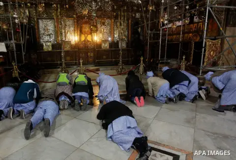 Africans Christian pilgrims pray at the Grotto in the Church of the Nativity, believed to be the birthplace of Jesus Christ, in the West Bank city of Bethlehem on December 22, 2016. Photo by Wisam Hashlamoun
