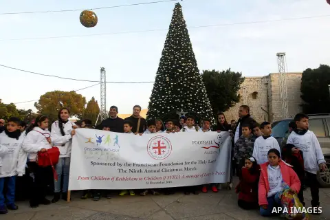 Palestinian Christian children take part at the ninth annual Christmas march past a Christmas tree at the Manger Square near the Church of the Nativity, revered as the site of Jesus Christ's birth, on December 22, 2016 i...