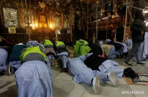 Africans Christian pilgrims pray at the Grotto in the Church of the Nativity, believed to be the birthplace of Jesus Christ, in the West Bank city of Bethlehem on December 22, 2016. Photo by Wisam Hashlamoun