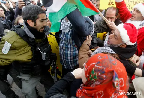 An Israeli border policeman scuffles with a Palestinian protester dressed up as Santa Claus during clashes at a demonstration next to a section of Israel's separation wall in the biblical town of Bethlehem, in the occupi...