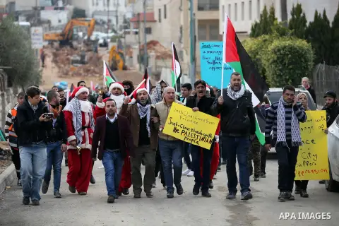 Palestinian demonstrators holding Palestinian flags take part in a protest next to a gate at a section of Israel's separation wall in the biblical town of Bethlehem, in the occupied West Bank, on December 23, 2016. Photo...