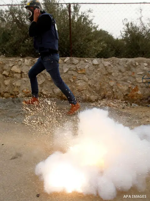 A Palestinian Journalist runs for cover form tear gas fired by fired by Israeli border guard during clashes at a demonstration next to a section of Israel's separation wall in the biblical town of Bethlehem, in the occup...