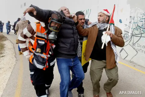 A Palestinian cameraman is evacuated after inhaling tear gas fired by fired by Israeli border guard during clashes at a demonstration next to a section of Israel's separation wall in the biblical town of Bethlehem, in th...