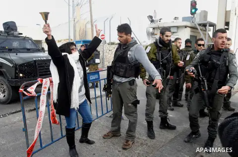 A Palestinian woman demonstrates next to a gate at a section of Israel's separation wall in the biblical town of Bethlehem, in the occupied West Bank, on December 23, 2016. Photo by Wisam Hashlamoun