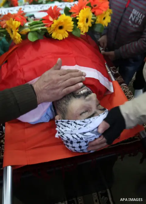 Mourners gather around the body of Palestinian Jihad Khalil, who according to the Israeli police was shot and killed by an Israeli security guard after Khalil tried to stab him last November, during his funeral after Isr...