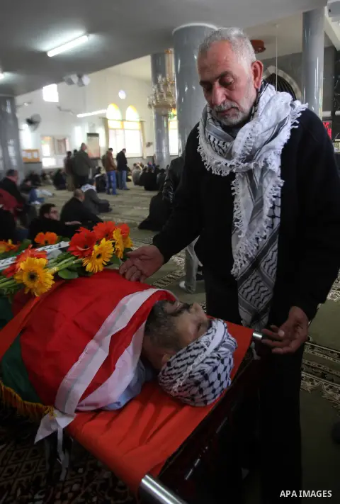 Mourners gather around the body of Palestinian Jihad Khalil, who according to the Israeli police was shot and killed by an Israeli security guard after Khalil tried to stab him last November, during his funeral after Isr...