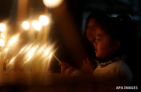 A visitor lights a candle inside the Church of the Nativity in the West Bank town of Bethlehem December 24, 2016. Photo by Shadi Hatem